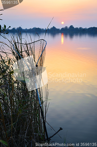 Image of Fishing rod and tank against the sunset on the lake fishing