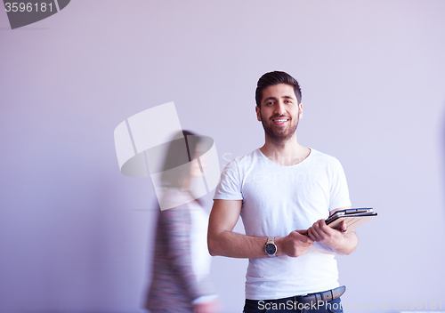 Image of student working on tablet, people group passing by