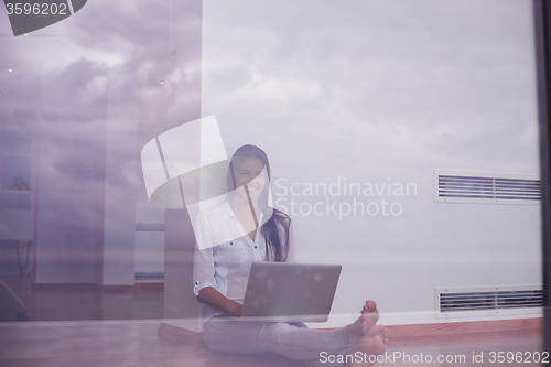 Image of relaxed young woman at home working on laptop computer