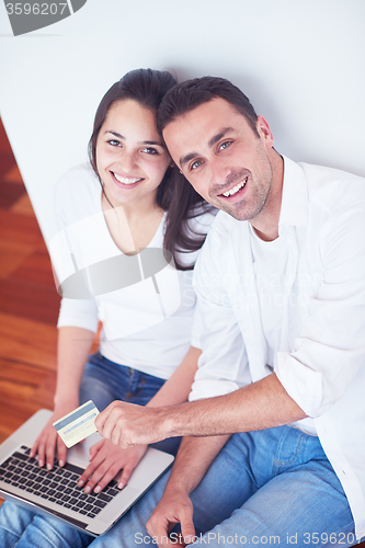 Image of relaxed young couple working on laptop computer at home