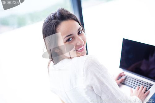 Image of relaxed young woman at home working on laptop computer