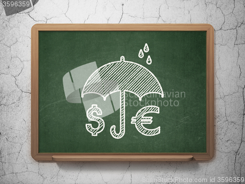 Image of Safety concept: Money And Umbrella on chalkboard background