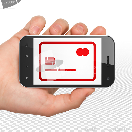 Image of Business concept: Hand Holding Smartphone with Credit Card on display