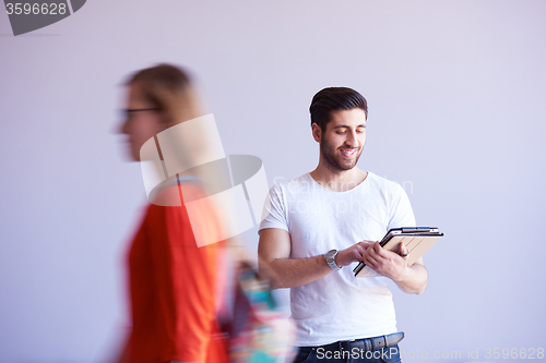 Image of student working on tablet, people group passing by