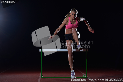 Image of woman athlete jumping over a hurdles