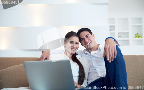 Image of relaxed young couple working on laptop computer at home