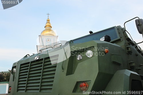 Image of Military vehicle close-up against the church bell tower