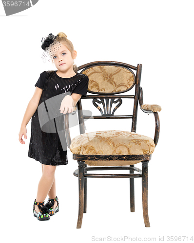 Image of Little Girl Standing near Antique Chair