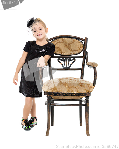 Image of Little Girl Standing near Antique Chair