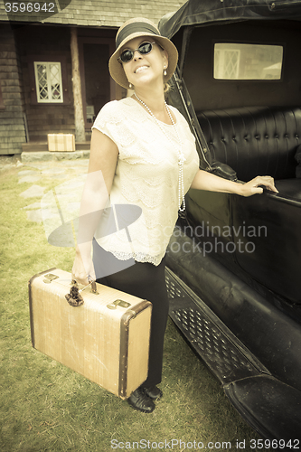 Image of Happy 1920s Dressed Girl Holding Suitcase Next to Vintage Car