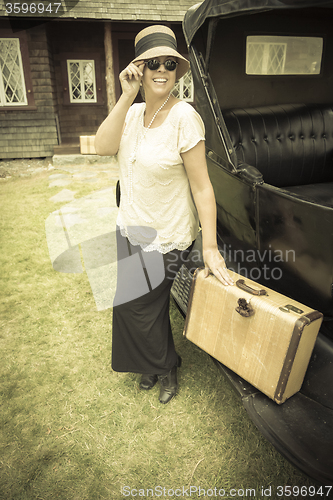 Image of Happy 1920s Dressed Girl Holding Suitcase Next to Vintage Car