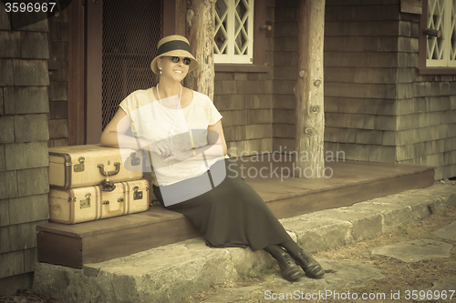 Image of 1920s Dressed Girl and Suitcases on Porch with Vintage Effect