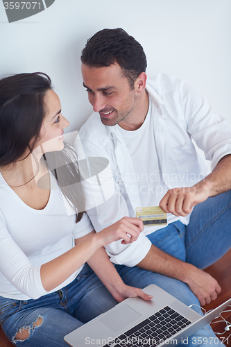 Image of relaxed young couple working on laptop computer at home