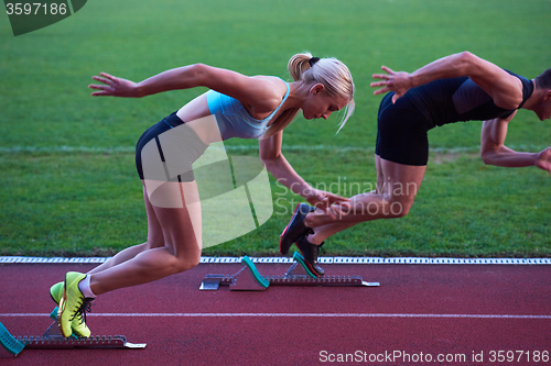 Image of woman group  running on athletics race track from start