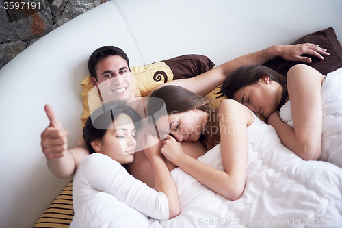 Image of handsome man in bed with three beautiful woman