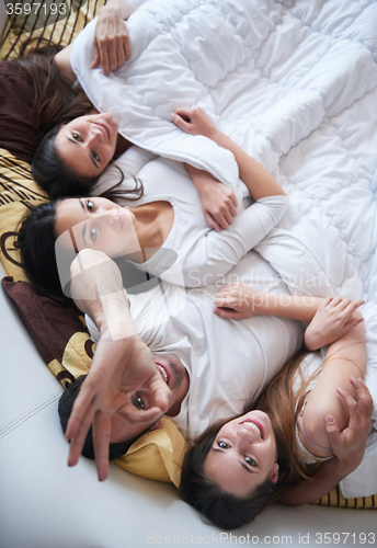 Image of handsome man in bed with three beautiful woman