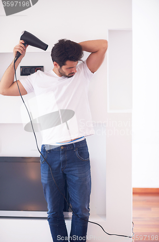 Image of handsome man using  hairdryer