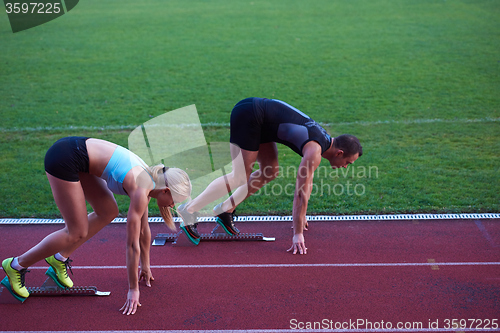 Image of woman group  running on athletics race track from start