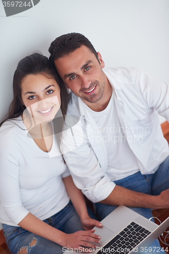 Image of relaxed young couple working on laptop computer at home