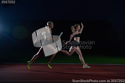 Image of athletic runners passing baton in relay race