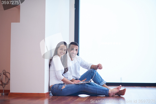 Image of relaxed young couple working on laptop computer at home