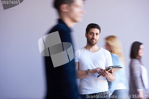 Image of student working on tablet, people group passing by