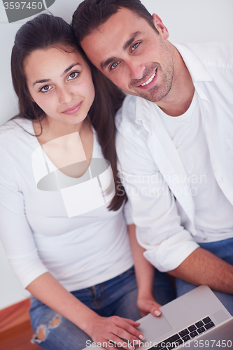 Image of relaxed young couple working on laptop computer at home