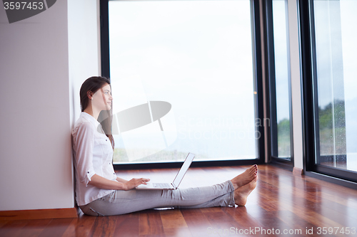 Image of relaxed young woman at home working on laptop computer