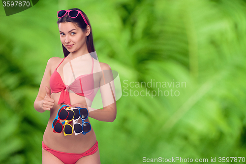 Image of Woman in bikini holding many colourful sunglasses