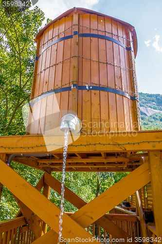 Image of wooden bucket with water running from faucet