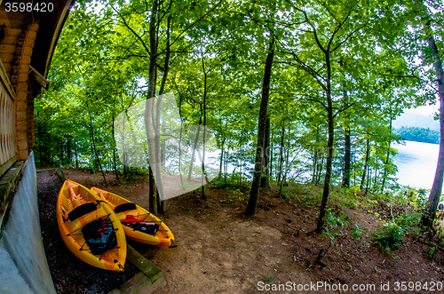 Image of two orange kayaks standing near cabin by the lake