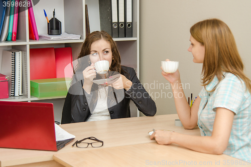 Image of Two employees of the office talk and drink tea