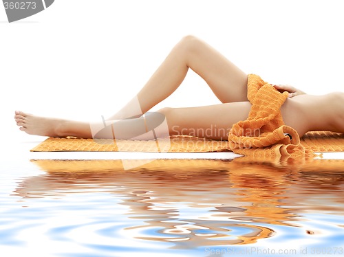 Image of long legs of girl with orange towel on white sand