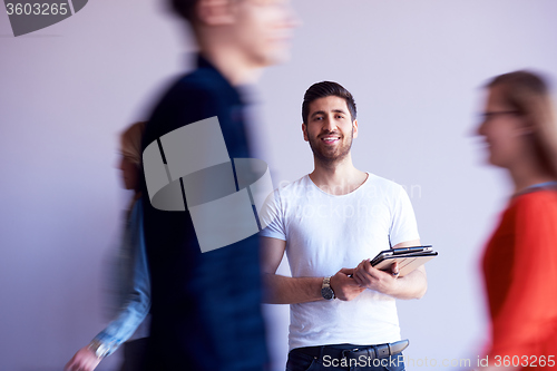 Image of student working on tablet, people group passing by