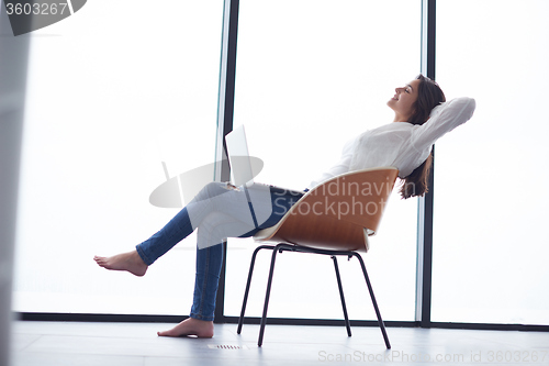 Image of relaxed young woman at home working on laptop computer