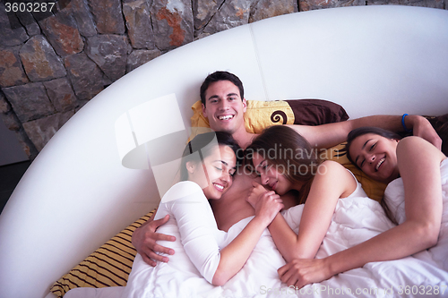 Image of handsome man in bed with three beautiful woman