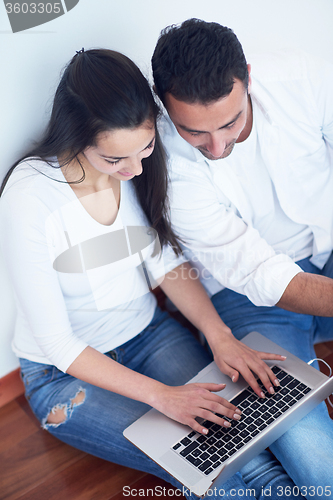 Image of relaxed young couple working on laptop computer at home