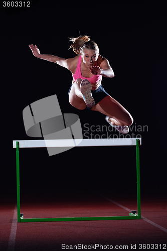 Image of woman athlete jumping over a hurdles