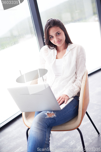 Image of relaxed young woman at home working on laptop computer