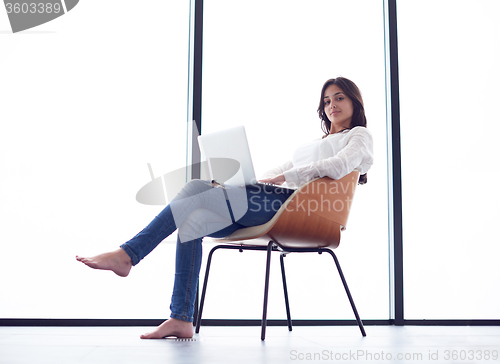 Image of relaxed young woman at home working on laptop computer