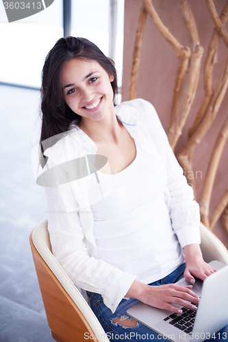 Image of relaxed young woman at home working on laptop computer