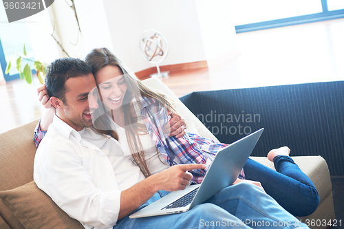 Image of relaxed young couple working on laptop computer at home