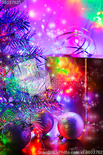 Image of Christmas tree, balls, box, lit by fairy lights