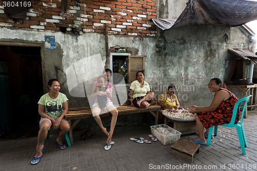 Image of Indonesian woman peel garlic in Manado shantytown