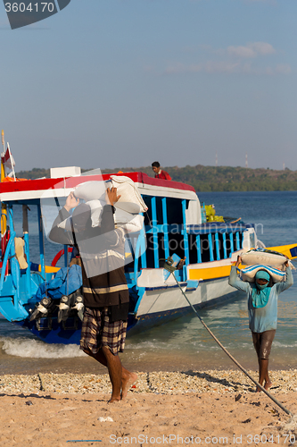 Image of Men transports cargo from ship