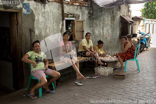 Image of Indonesian woman peel garlic in Manado shantytown