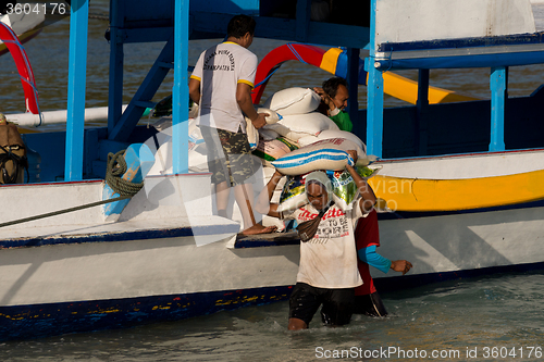 Image of Men transports cargo from ship