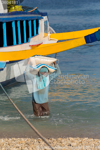 Image of Men transports cargo from ship