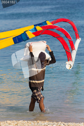 Image of Men transports cargo from ship