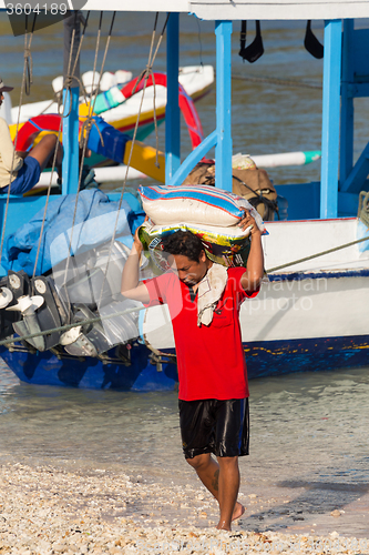 Image of Men transports cargo from ship